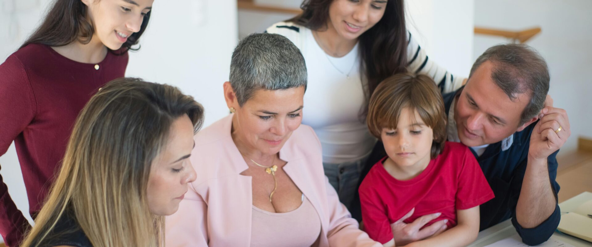 A woman in pink blazer talking to the family sitting beside her