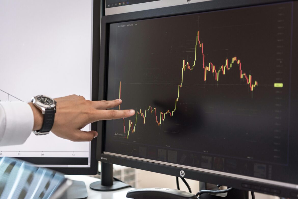 Hand on screen with charts of cryptocurrency