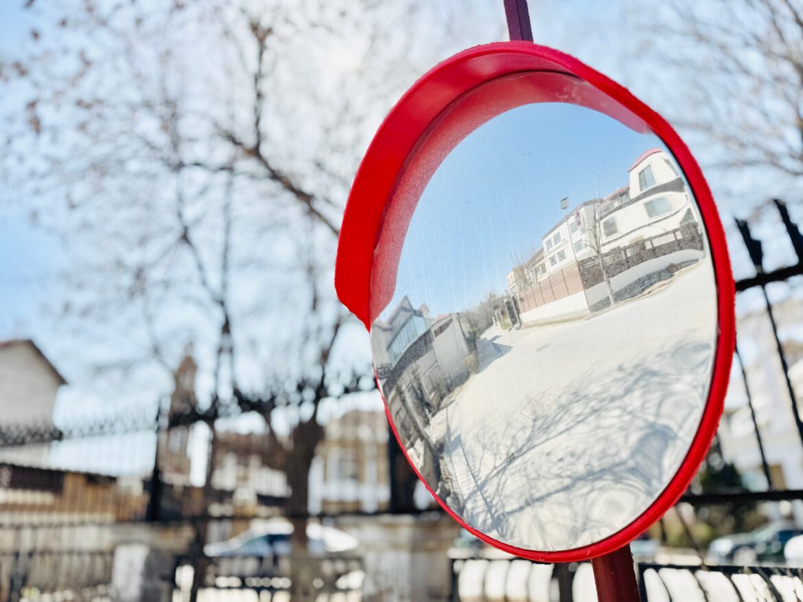 Convex street mirror reflection in urban setting