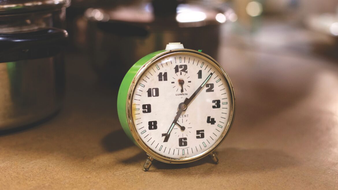 Green alarm clock near the stainless steel cooking pots
