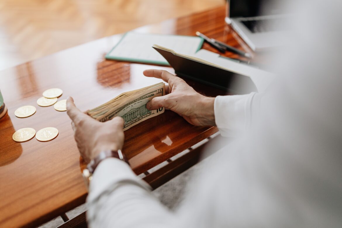 A person holding a paper money on the table