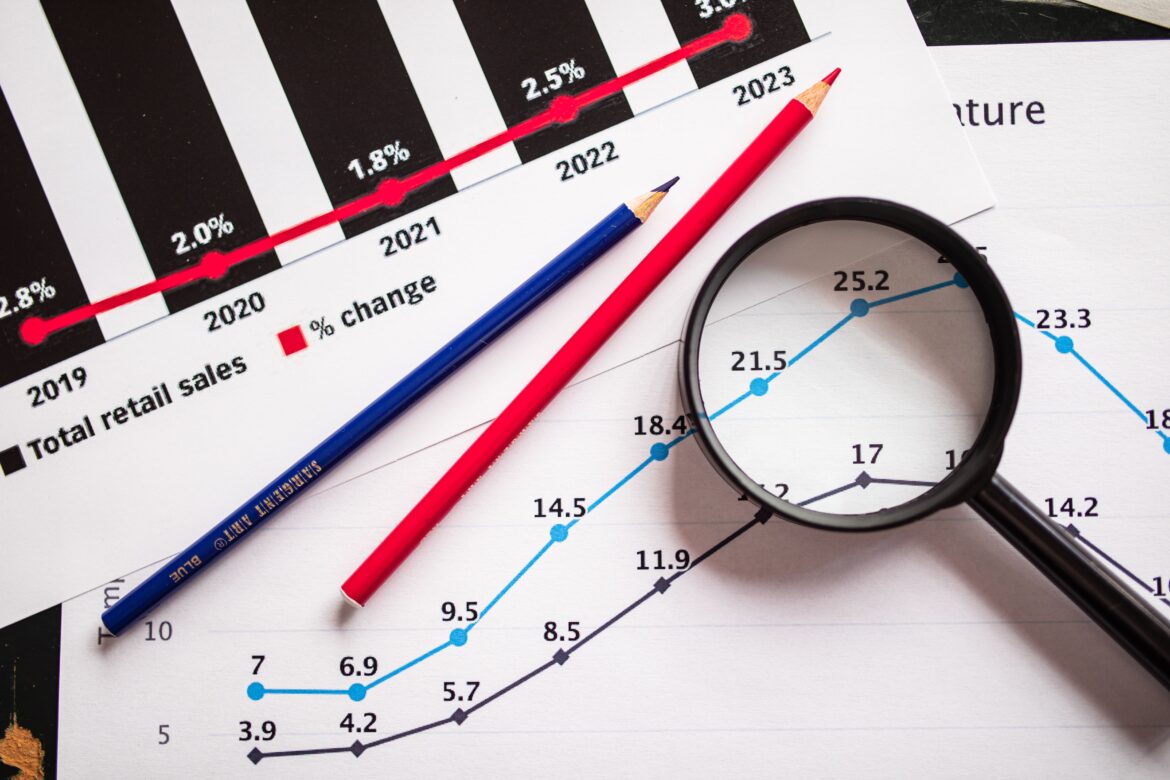 Colored pencils and a magnifying glass over documents with graphs