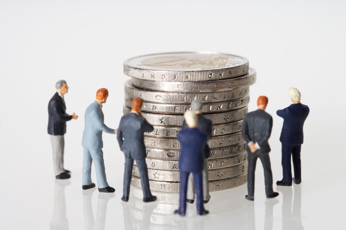 Human toys standing beside silver coins