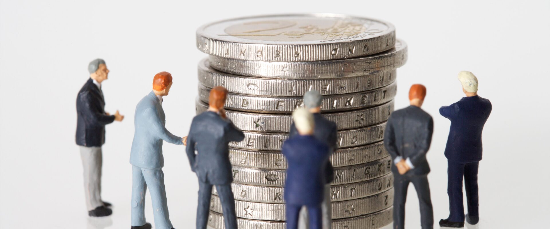 Human toys standing beside silver coins
