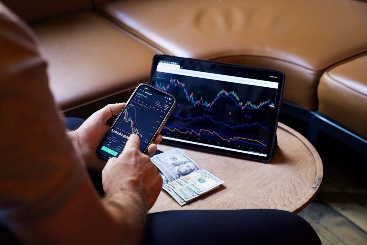 Man looking at the stock charts on the phone and tablet