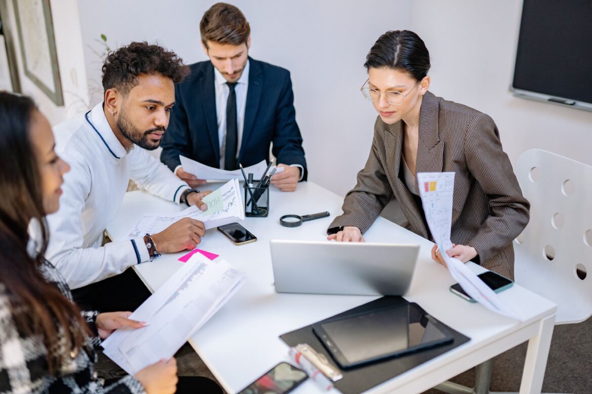 Business people sitting at white table looking at laptop