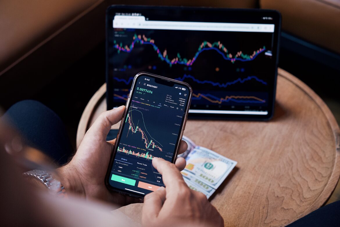 Man looking at the stock charts on the phone and tablet