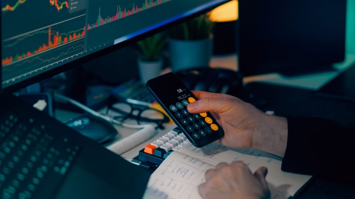 Finance professional analyzing data on calculator and monitor