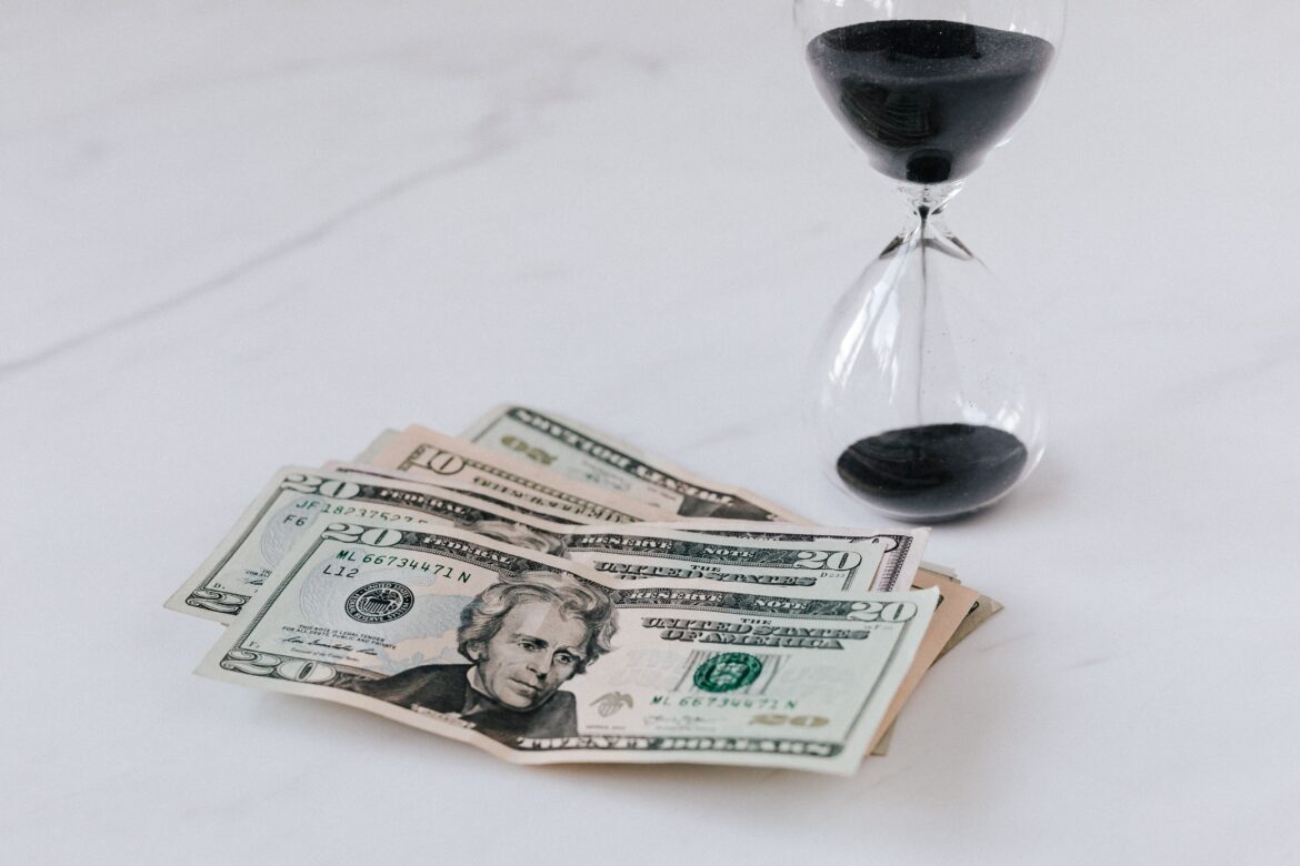 Hourglass near heap of american dollars