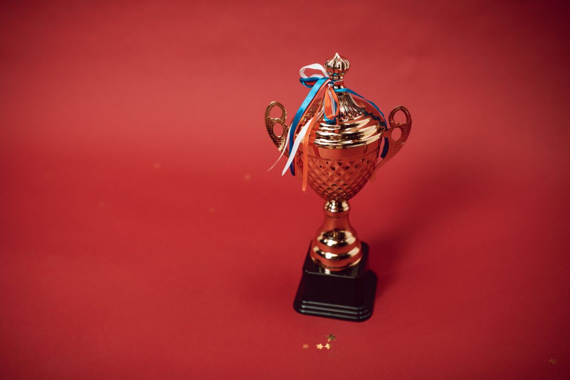 A trophy with tied ribbons on red background