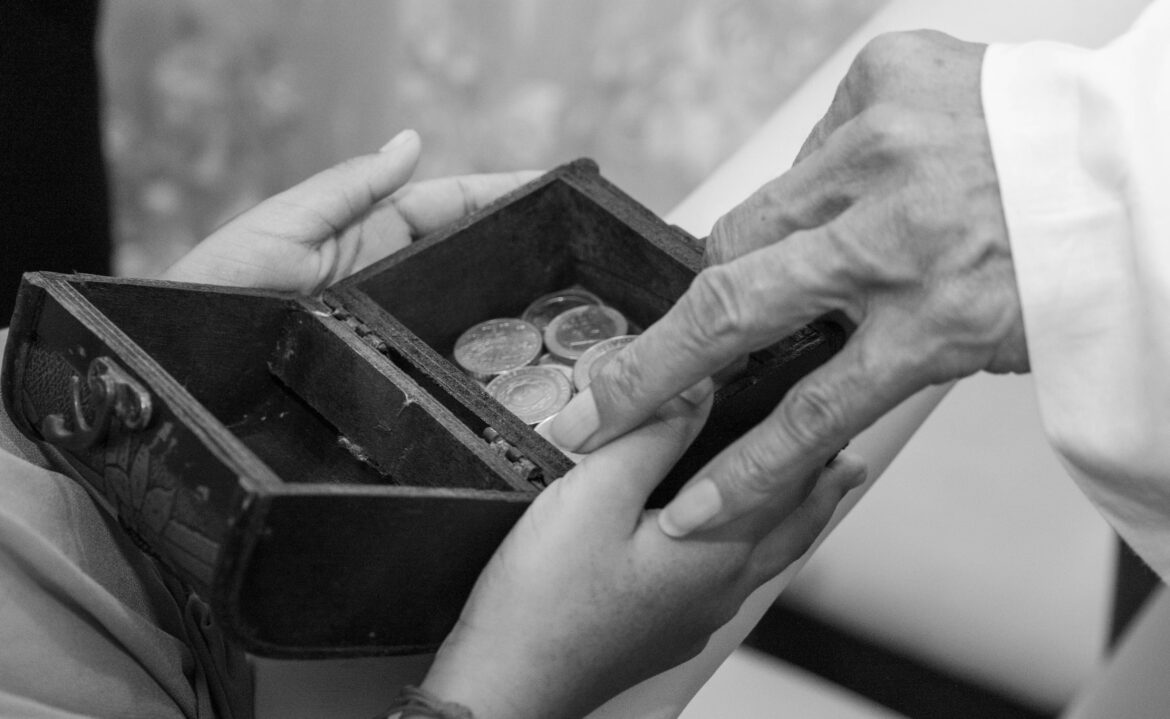 Hands holding coins in wooden box black and white