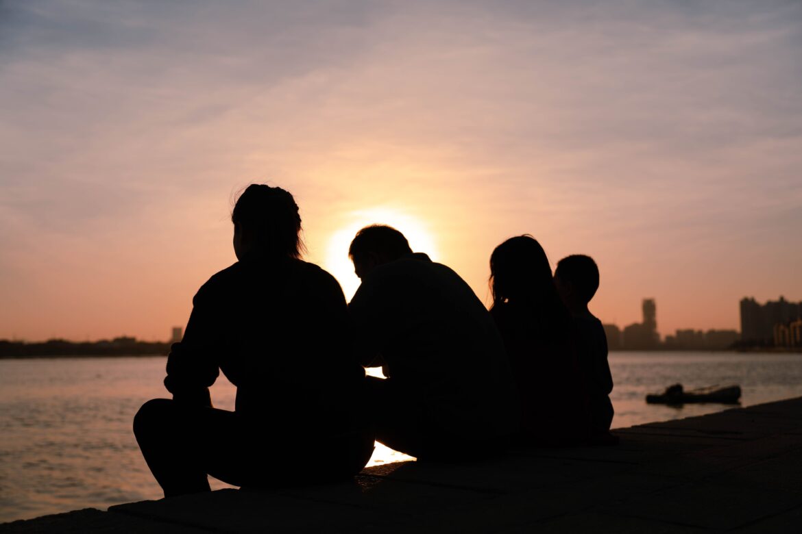 Peaceful family silhouette at sunset by water