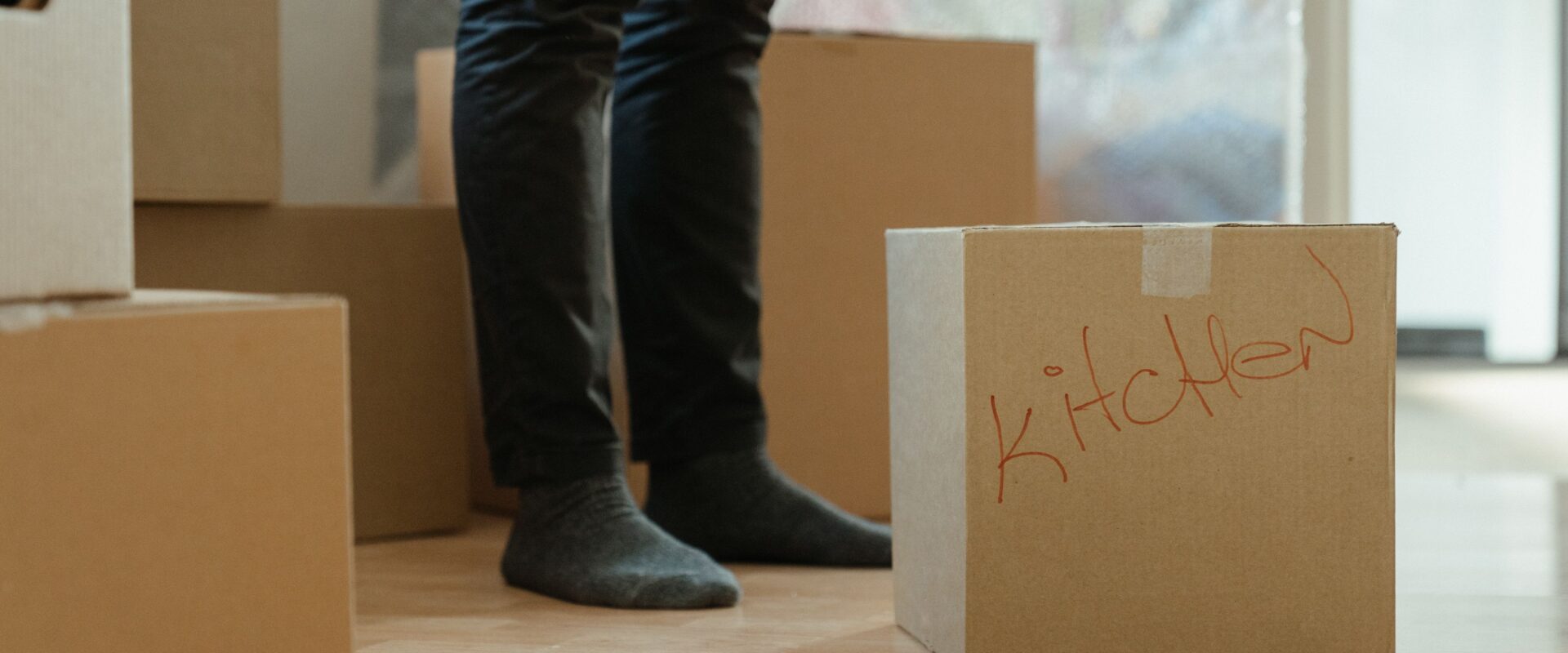 Person in blue denim jeans standing beside brown cardboard box