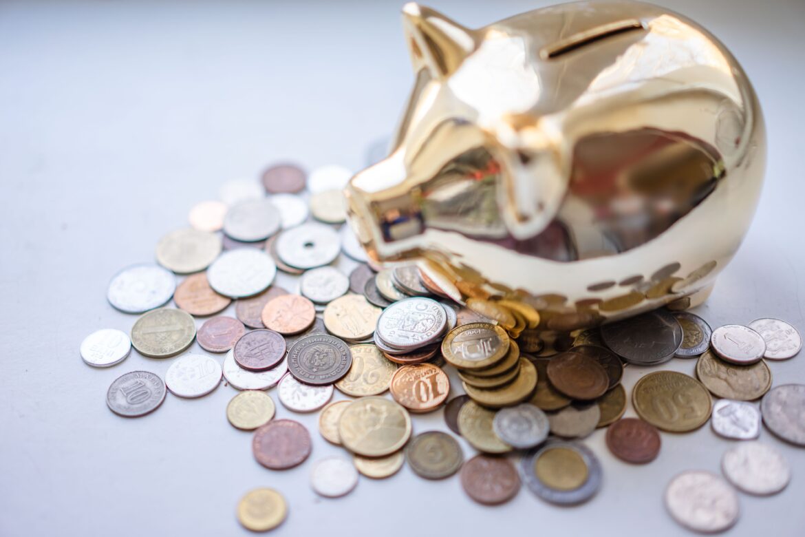 Silver and gold coins near piggy bank