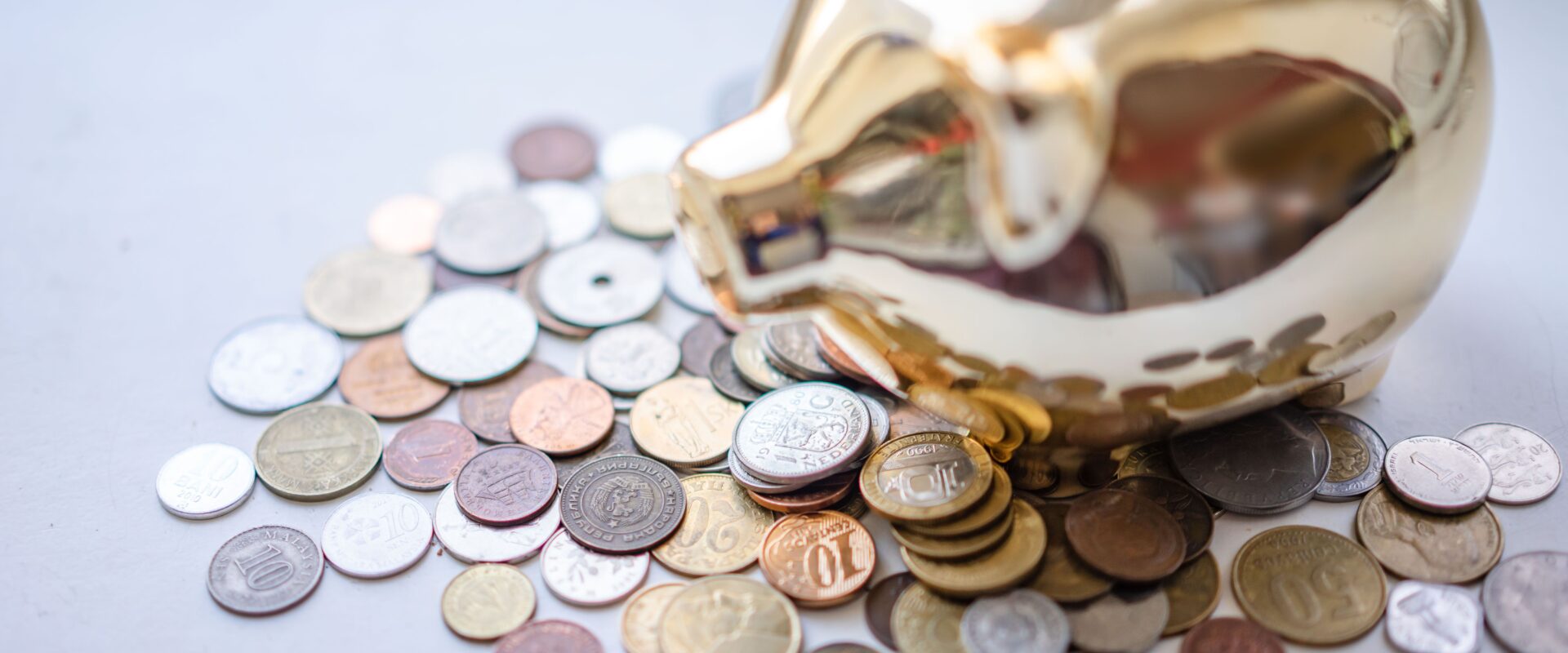 Silver and gold coins near piggy bank