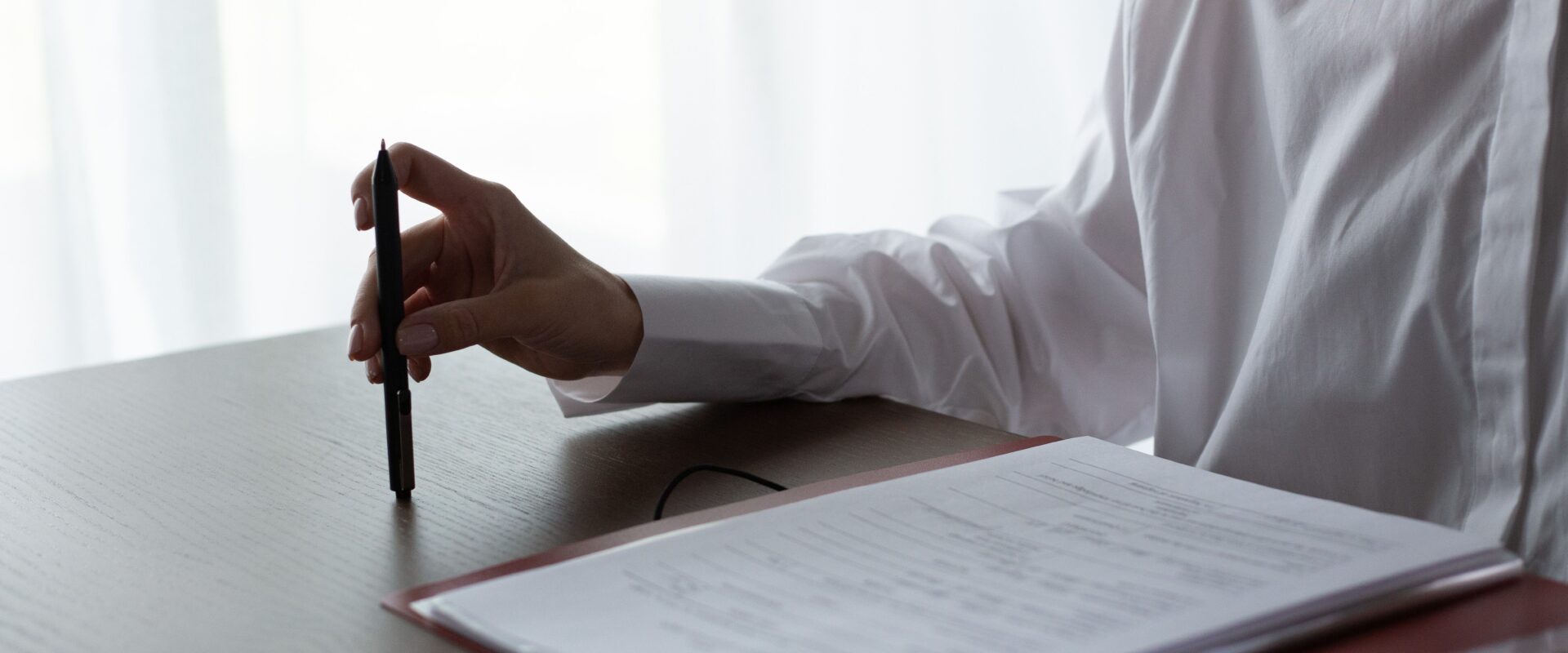 Unrecognizable hand of woman sitting at table and reviewing documents